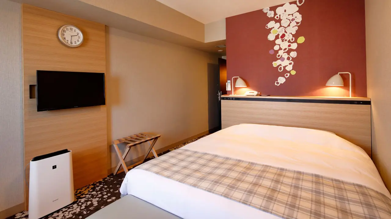 A cosy queen double room at Hotel Monte Hermana with a plaid bed runner, decorative red wall, and warm lighting