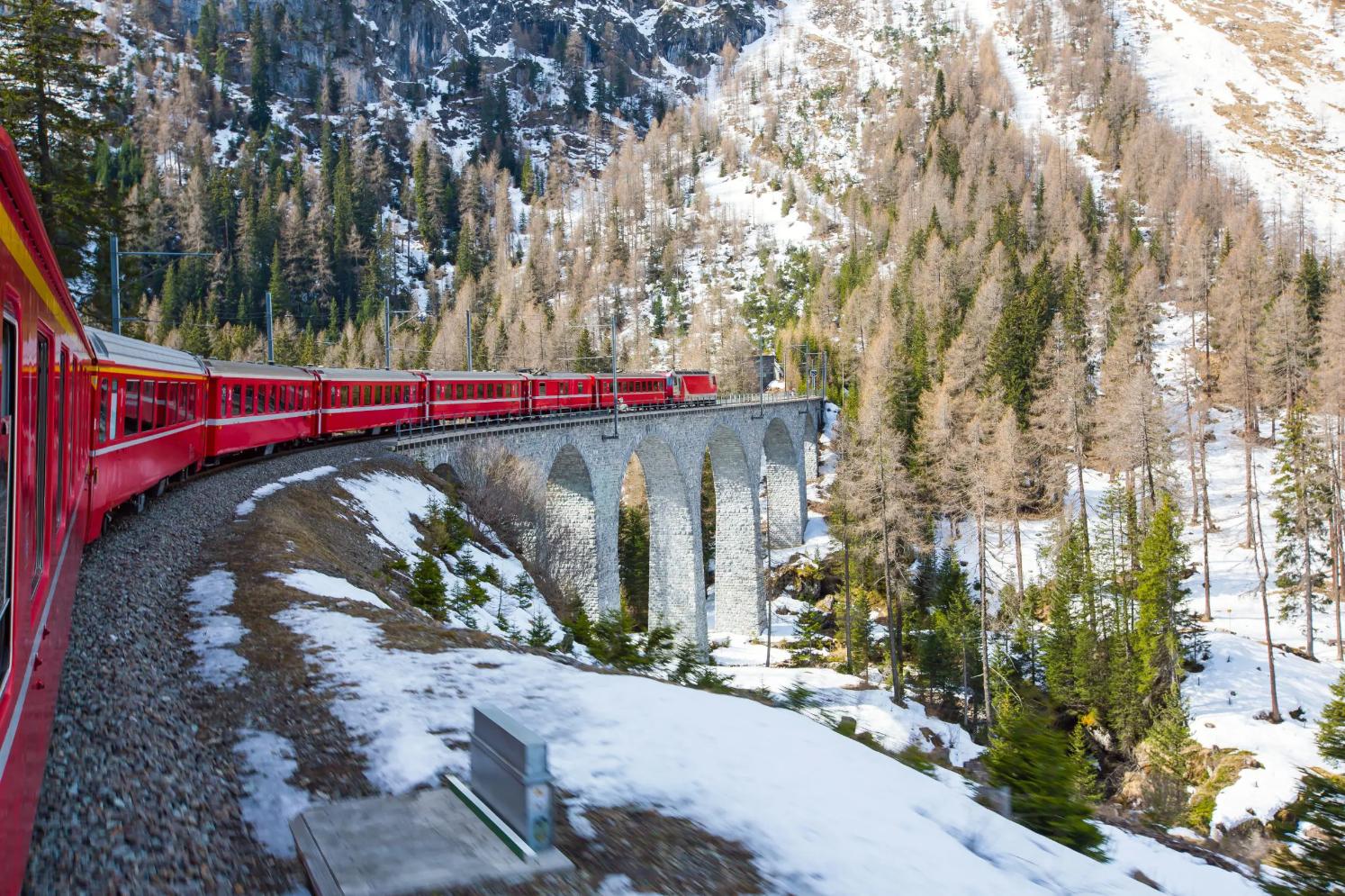 The Bernina Express train winding through snow-covered Alpine mountains on a scenic railway route