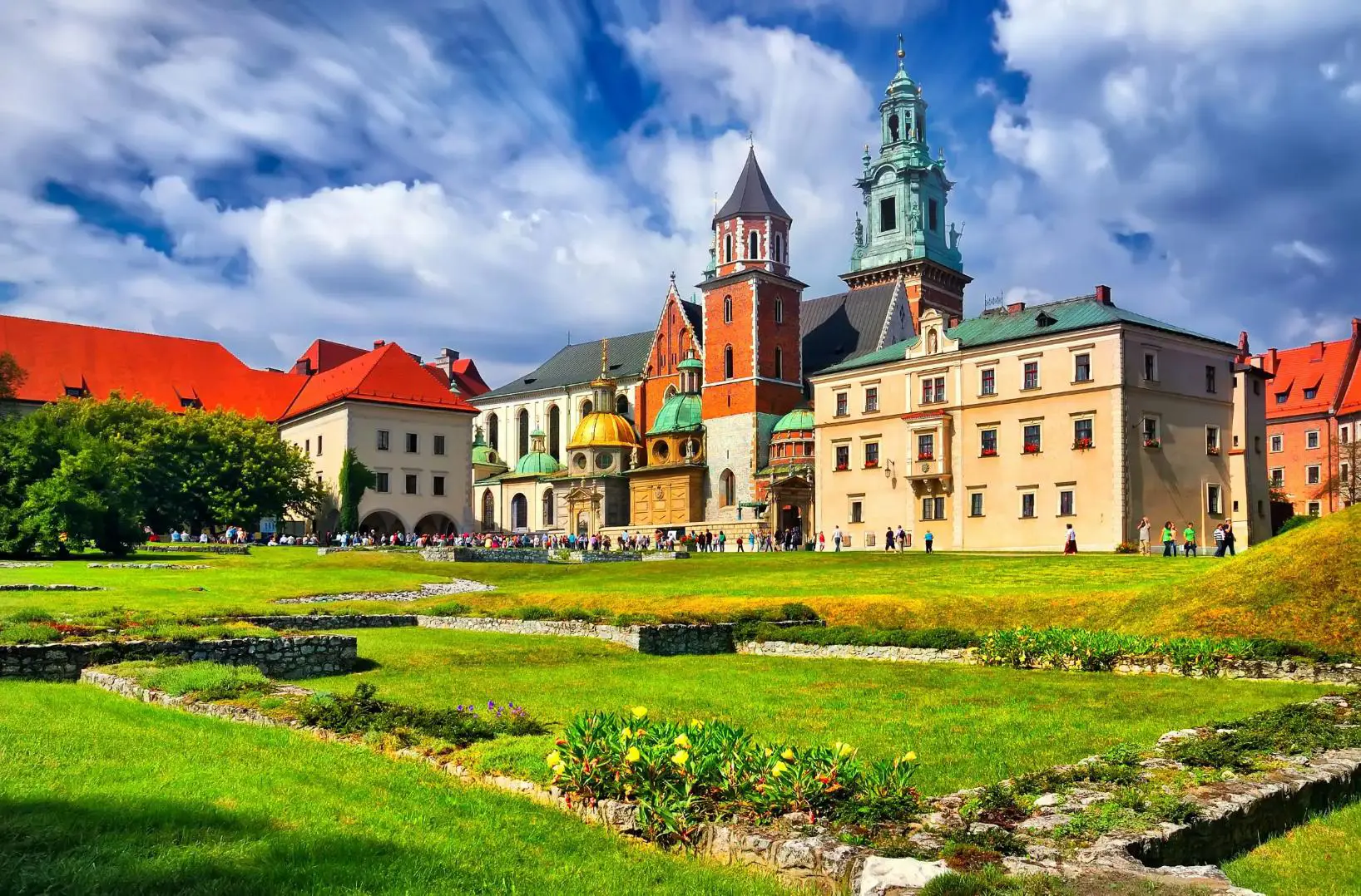 Wawel Castle in Kraków, Poland, showcasing its historic towers and red-brick walls beneath a cloudy blue sky