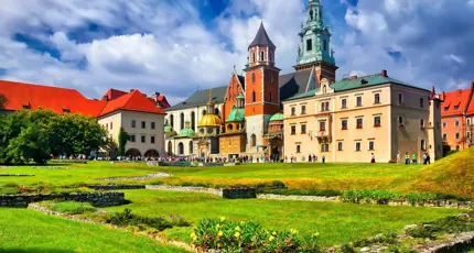 Wawel Castle in Kraków, Poland, showcasing its historic towers and red-brick walls beneath a cloudy blue sky
