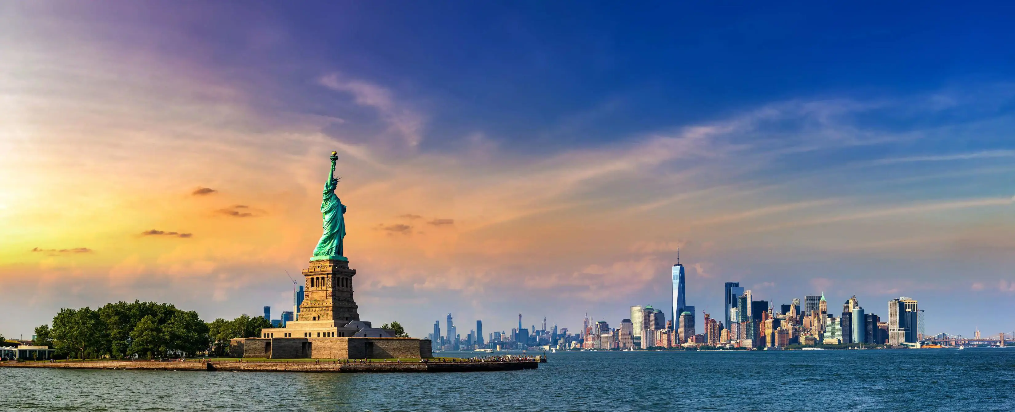 The Statue of Liberty standing on Liberty Island with Lower Manhattan’s skyline visible in the background across the water