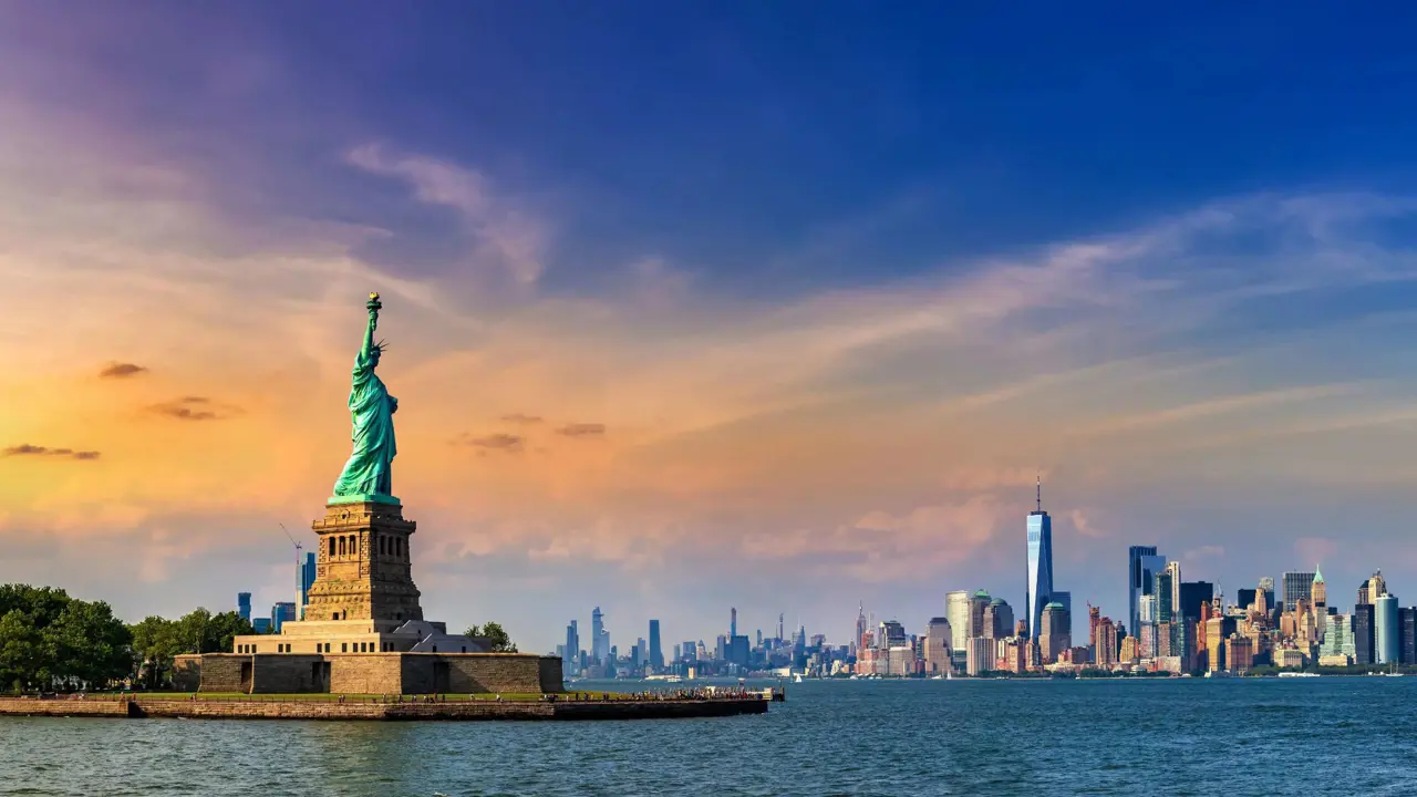 The Statue of Liberty standing on Liberty Island with Lower Manhattan’s skyline visible in the background across the water