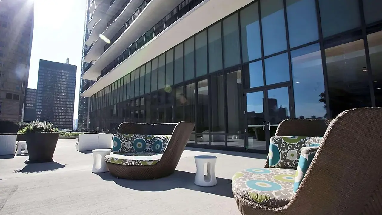A terrace at Radisson Blu Aqua Hotel, Chicago, featuring modern outdoor seating, sleek design, and views of the hotel’s large glass entrance and surrounding cityscape