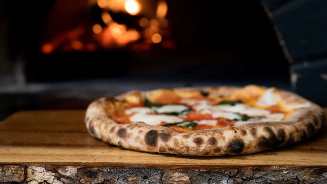 Pizza with woodfire oven in the background in Naples, Italy