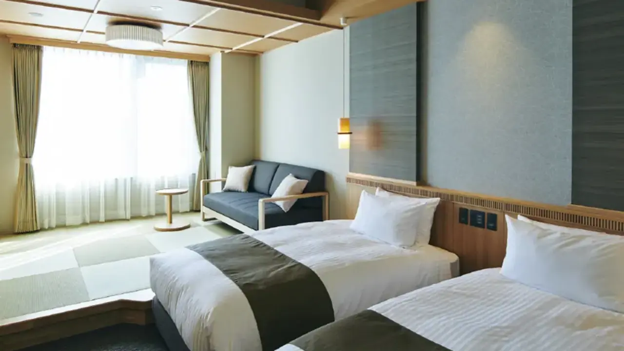 Bright and elegant twin bedroom in Hotel Kowakuen Haruka, with two beds, a sofa by the window, and a blend of modern and traditional Japanese design elements