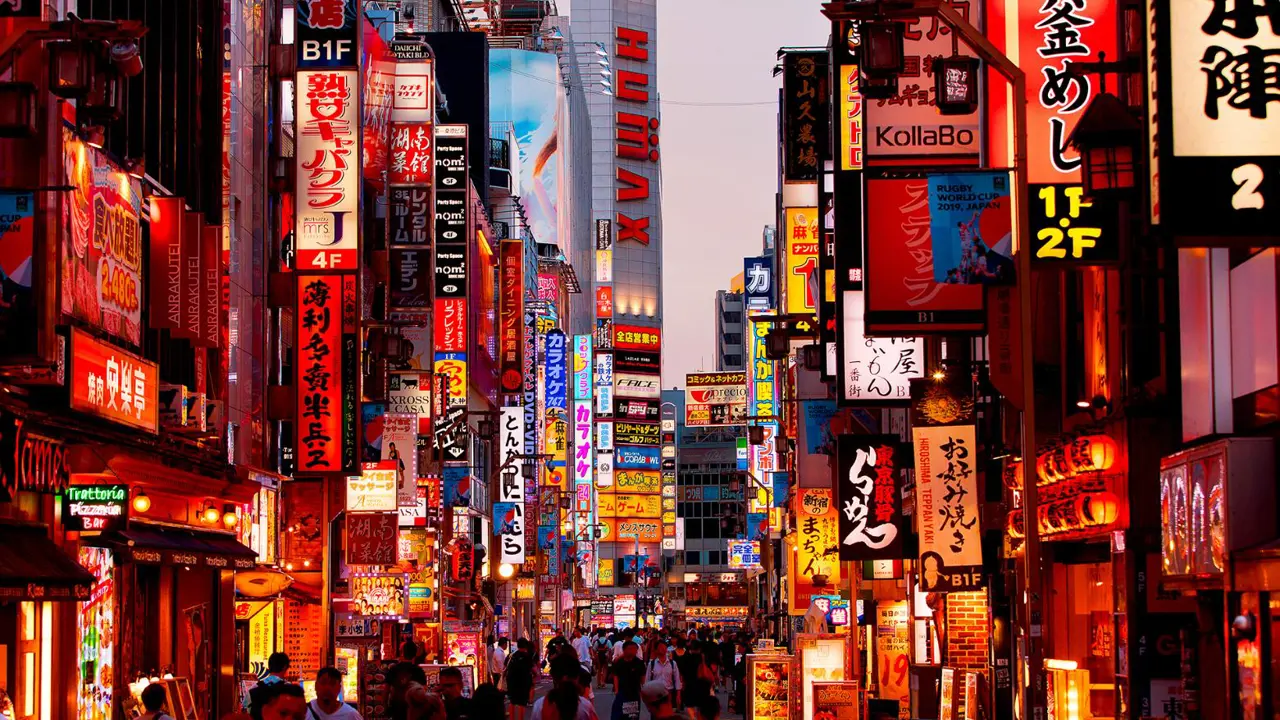 bustling cityscape of Tokyo at dusk, featuring bright lights, high-rise buildings, and busy streets filled with cars and pedestrians