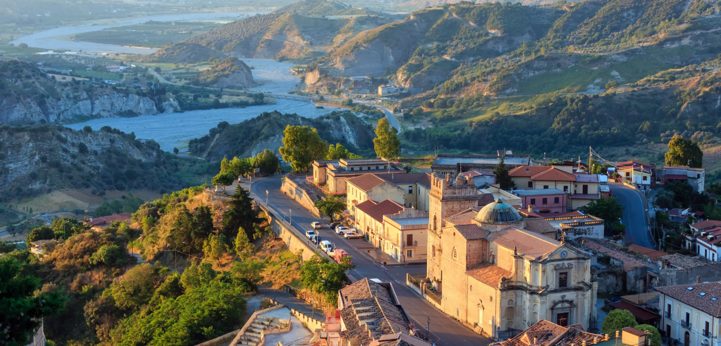 Aerial View Of Calabria Italy, showing the town and the mountains and bodies of water behind it 