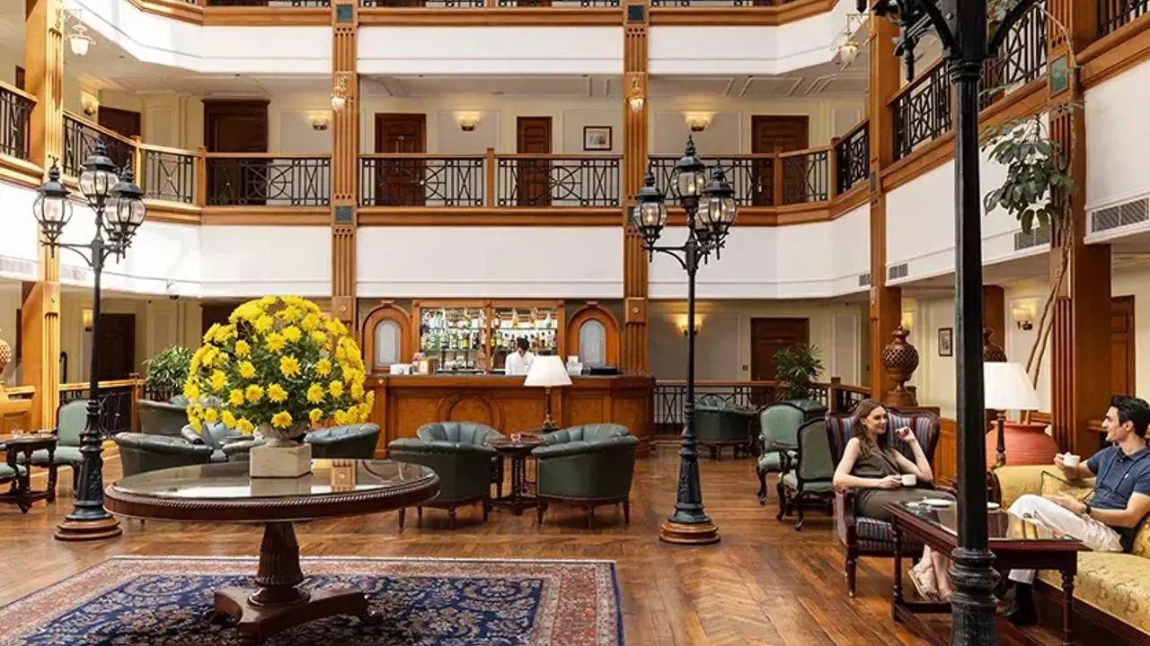 Lounge area of the Oberoi Cecil, Shimla, with tiered rooms surrounding the space, comfortable seating, wooden floors, and yellow flowers on the central table