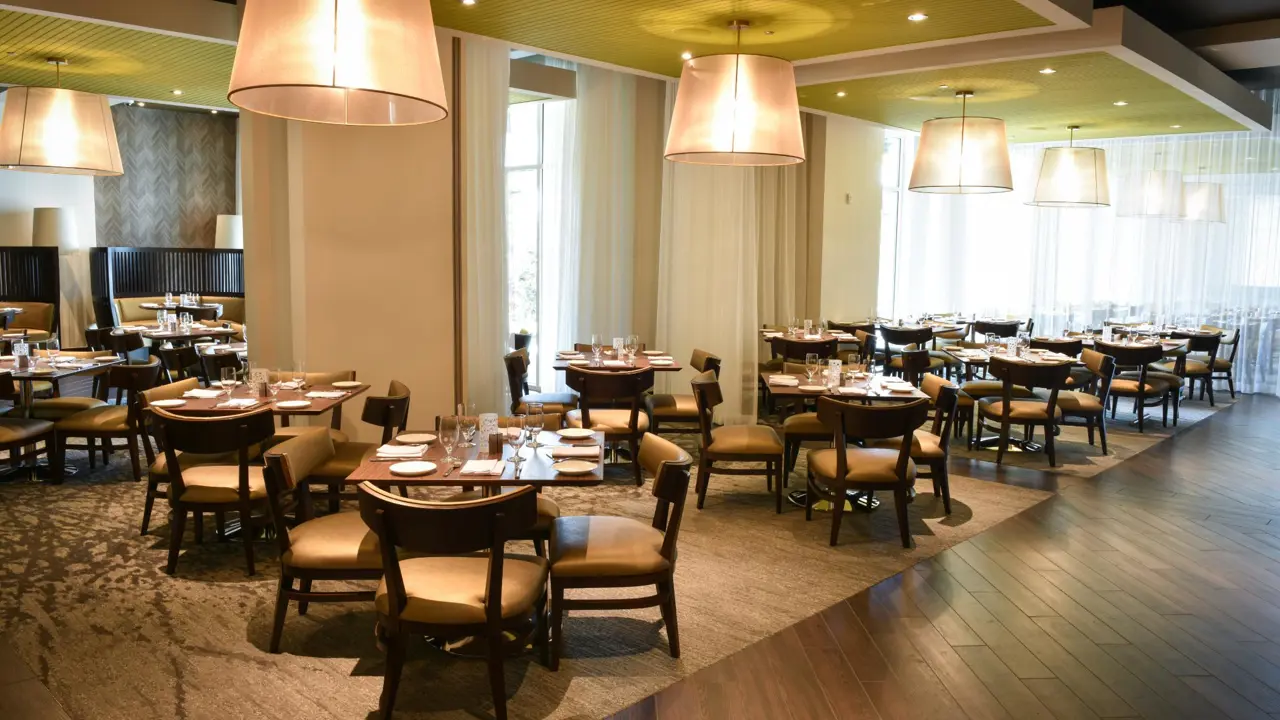Modern restaurant at The Guest House at Graceland in Memphis, Tennessee, with wooden tables, cushioned chairs, soft pendant lighting, and a calm, upscale atmosphere