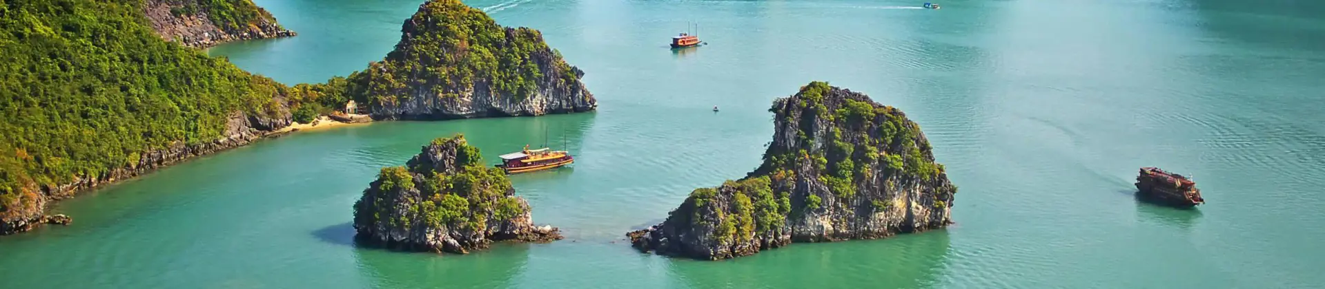 Traditional wooden boats sailing among limestone islands in Ha Long Bay, Vietnam