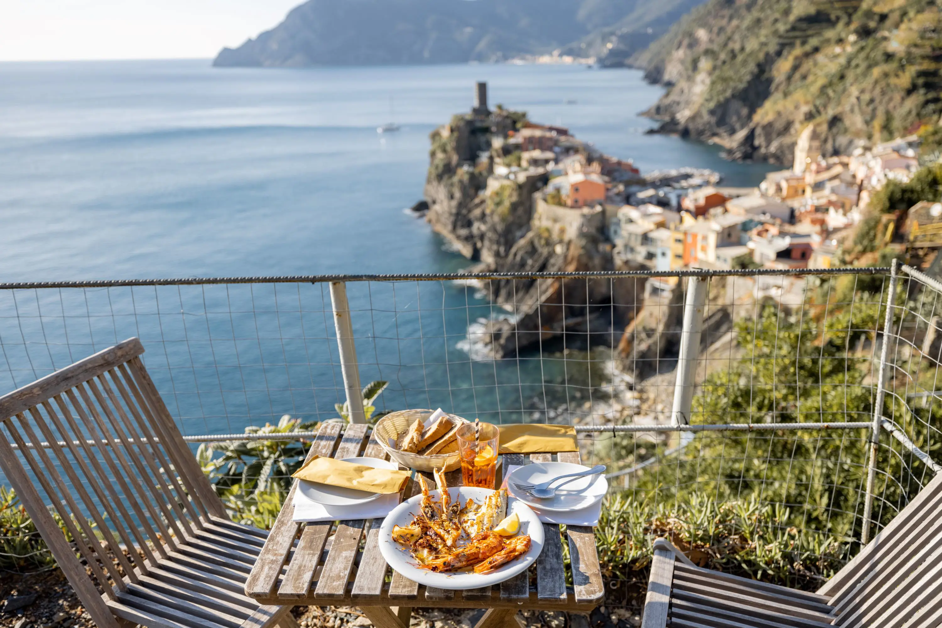 Table of food on a balcony with the view of the sea and the town of Clinque Terre