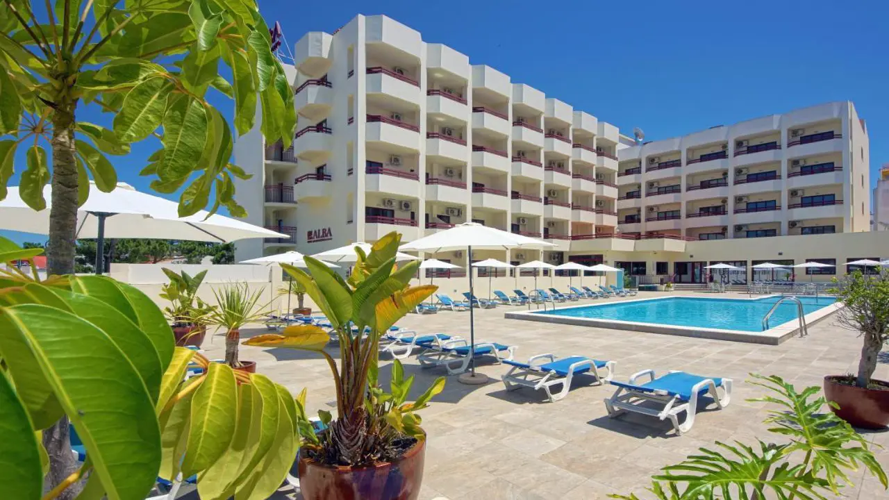Outdoor pool at Hotel Alba in Portugal, surrounded by hotel room balconies, with sunloungers arranged around the poolside