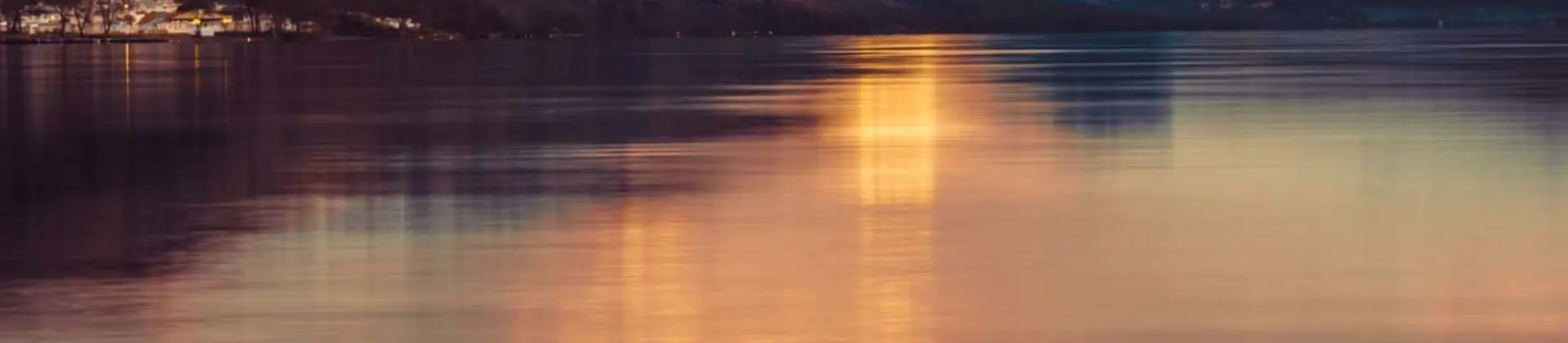 Loch Lomond at sunset, with snowy mountains in the distance