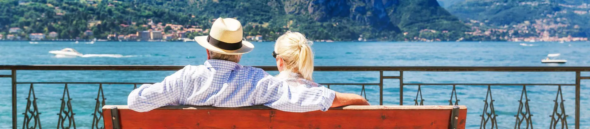 The back of a couple sat on a bench looking out to Lake Como