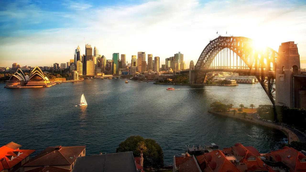 The Sydney Opera House beside Sydney Harbour with the city skyline in the background.
