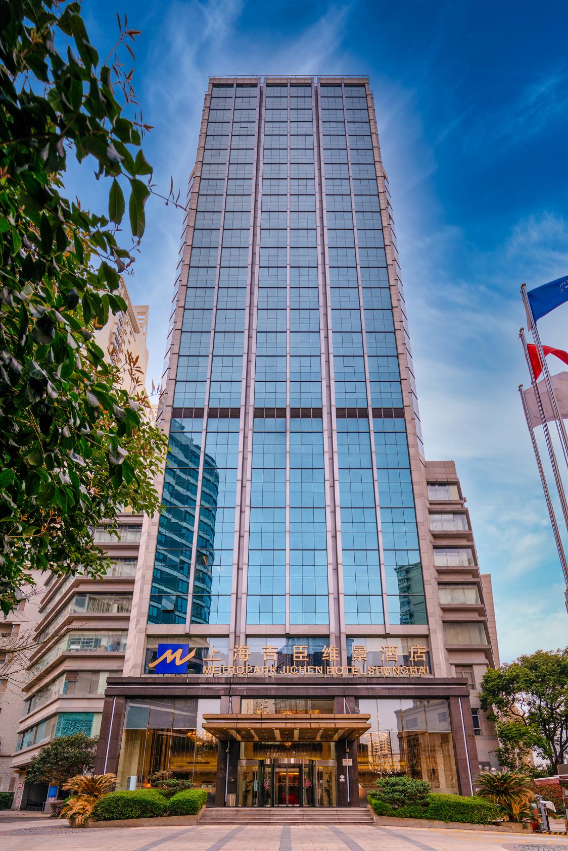 The modern exterior of Shanghai Metropark Jichen Hotel featuring a grand entrance and glass windows up to the top of the tower building