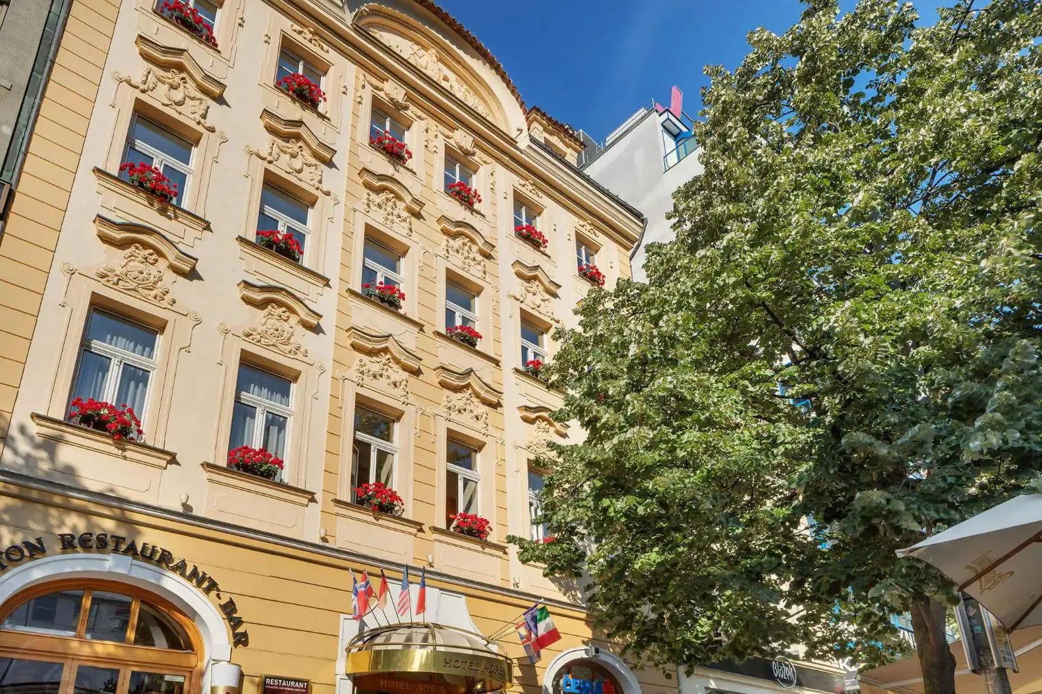 Façade of Hotel Adria in Prague with flower-adorned windows and ornate details