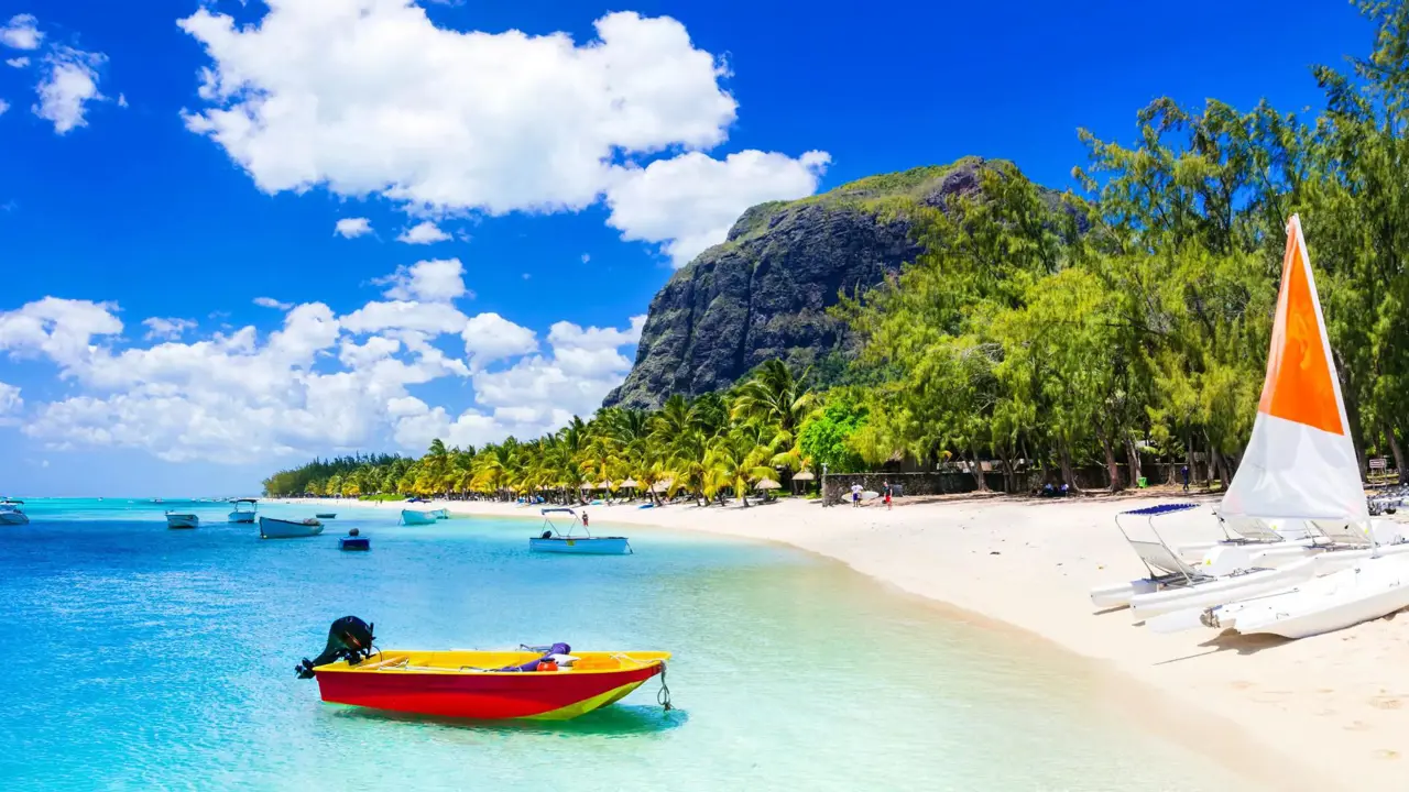 View of Mauritius featuring clear blue water, several boats floating on the sea, and a yacht on the sandy shore