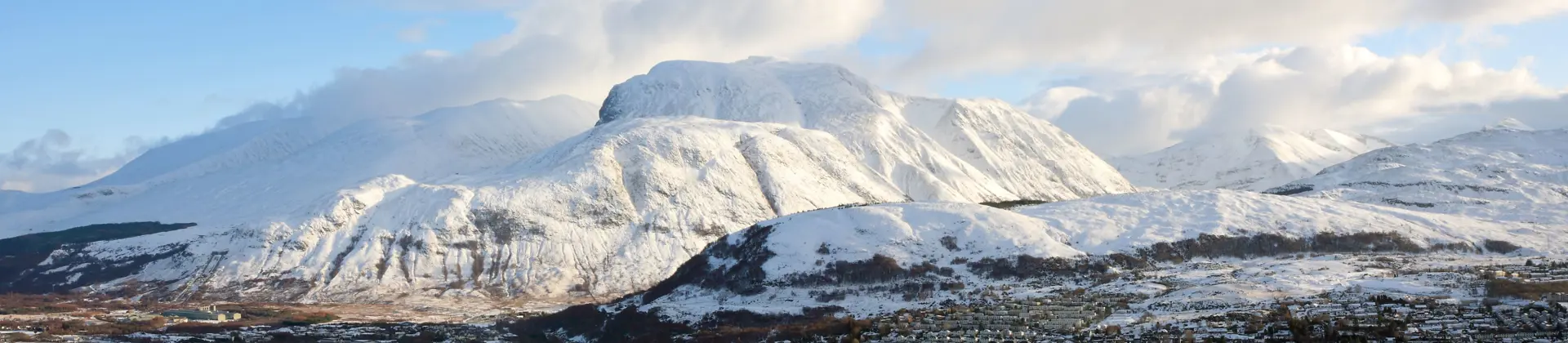 View of Fort William village with snowy Ben Nevis mountain behind 