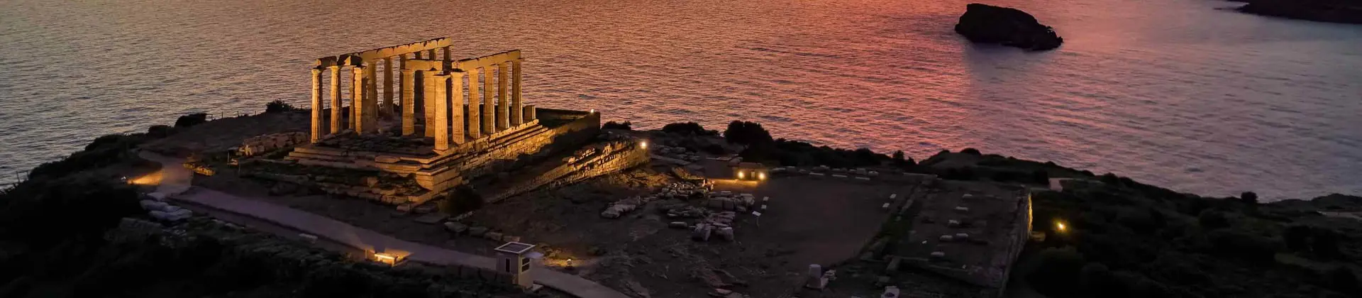 High angle view of some ruins on the land's edge, with the view of the sea and orange sunset 