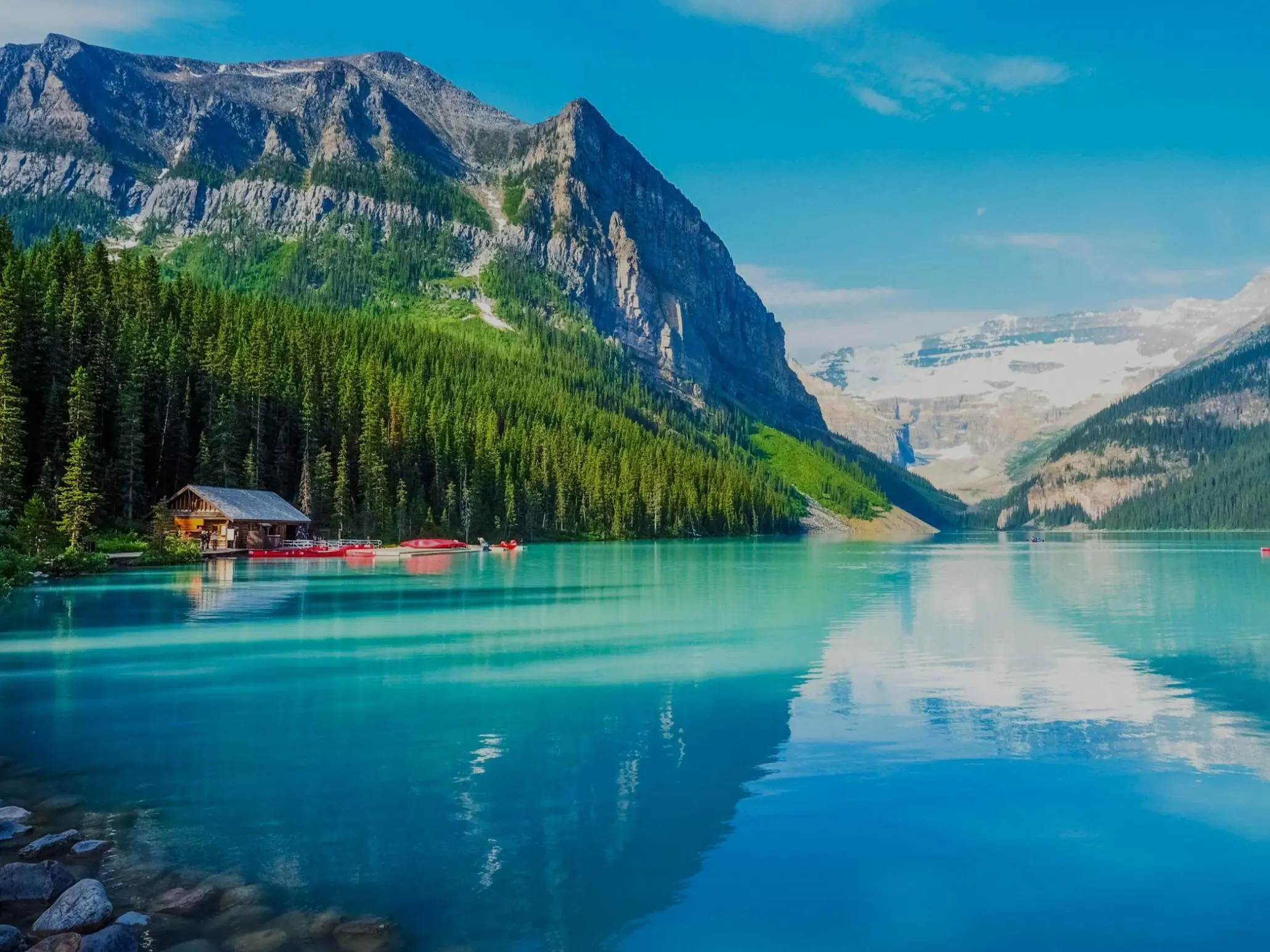 Turquoise waters of Lake Louise surrounded by forested slopes and snow-capped mountains