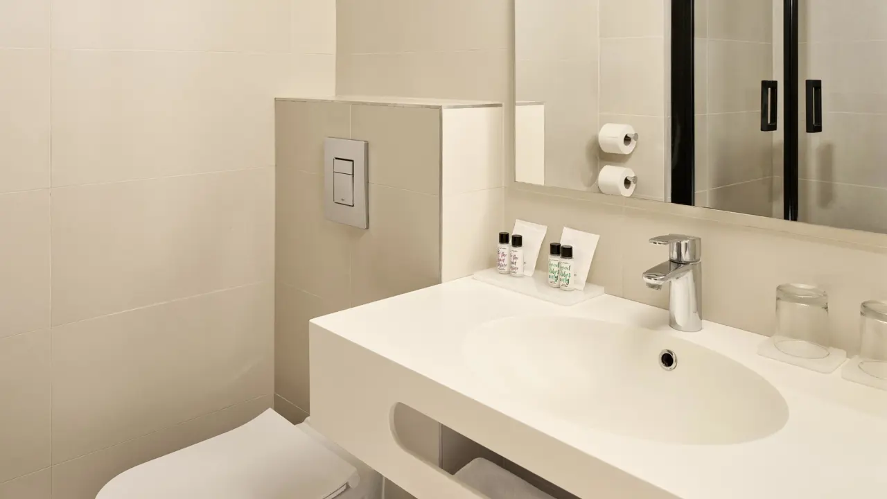 Standard bathroom featuring white fixtures complimented by soft beige tiles at Hotel Horizont, Baška Voda