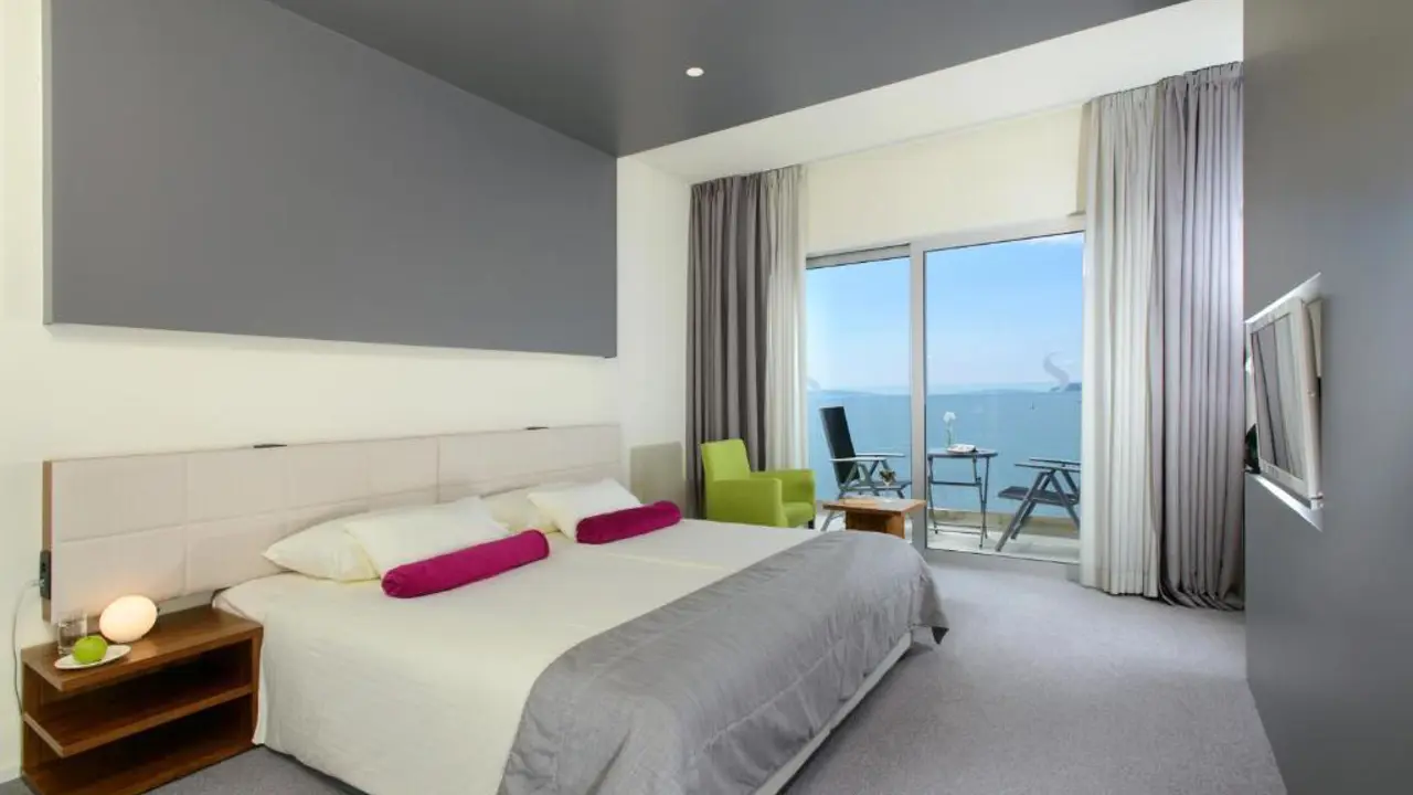 A contemporary room at Hotel Split, Podstrana, with a spacious double bed, sleek grey-and-white décor, and a private balcony offering uninterrupted views of the Adriatic Sea