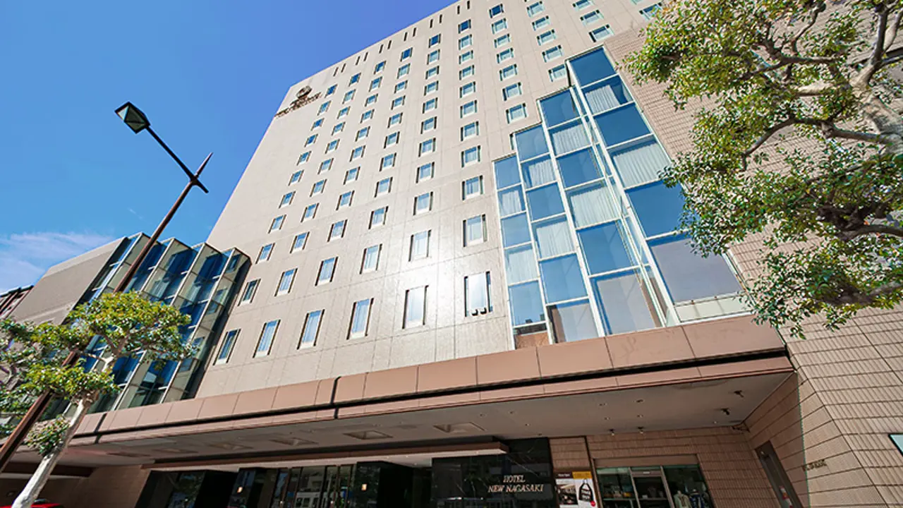 Exterior of Hotel New Nagasaki, a tall modern building with a light façade and rows of windows under a clear blue sky