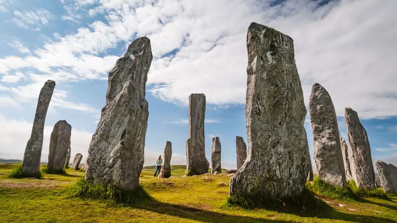Low angle shot of standing stones, with a woman standing next one