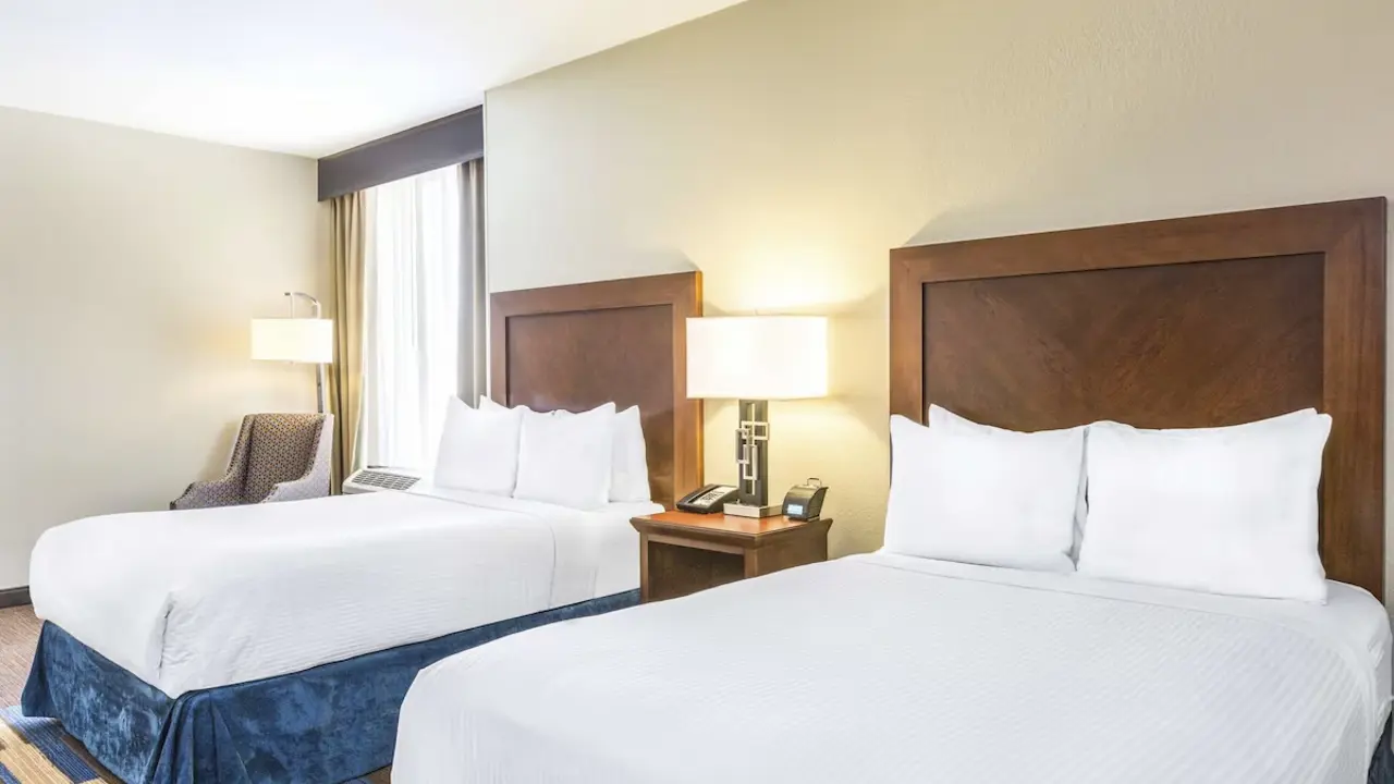 Spacious hotel room at Wyndham New Orleans French Quarter featuring two double beds with crisp white linens and large window