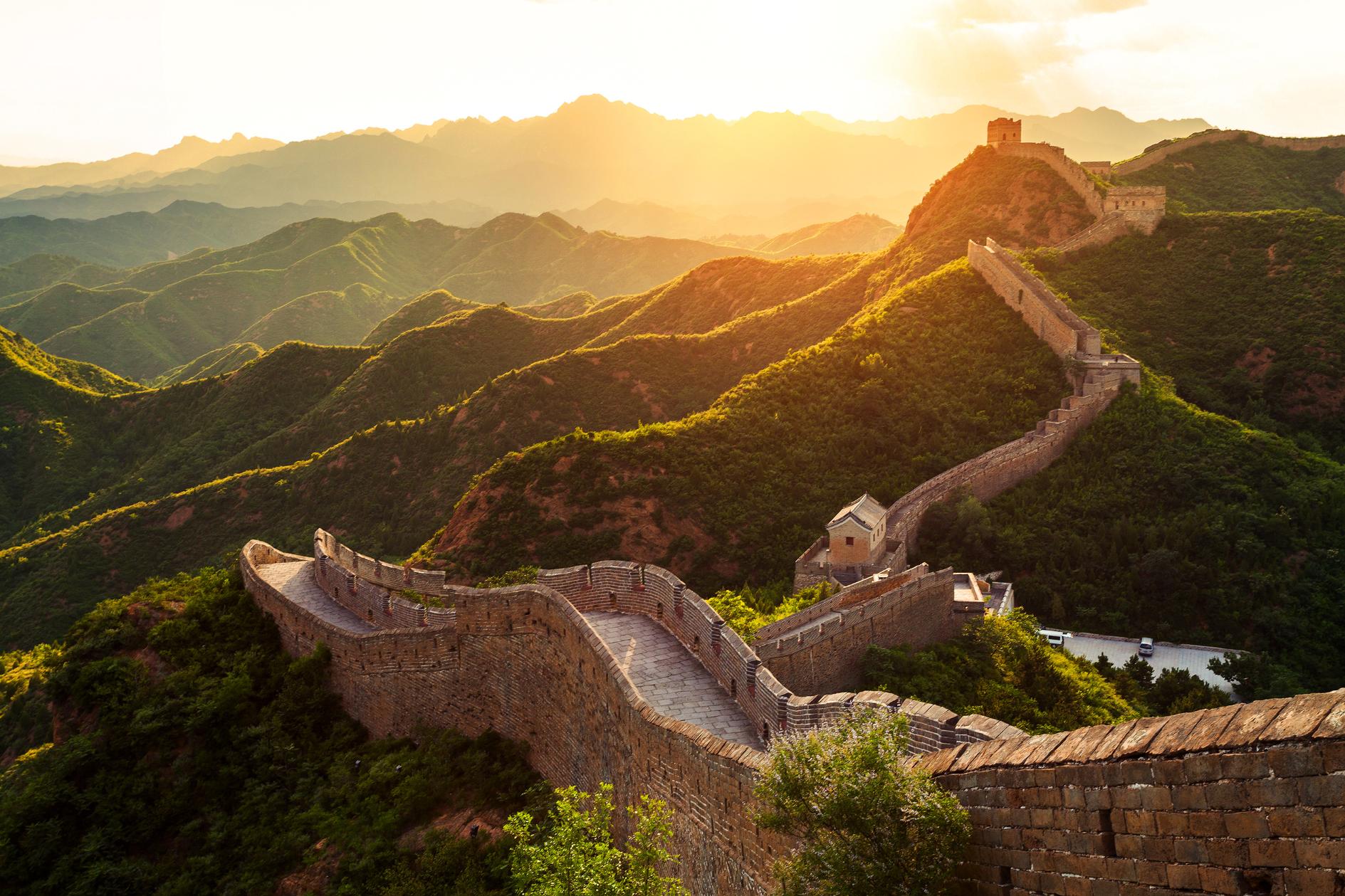 The Great Wall winding over green mountains at sunset, Beijing, China