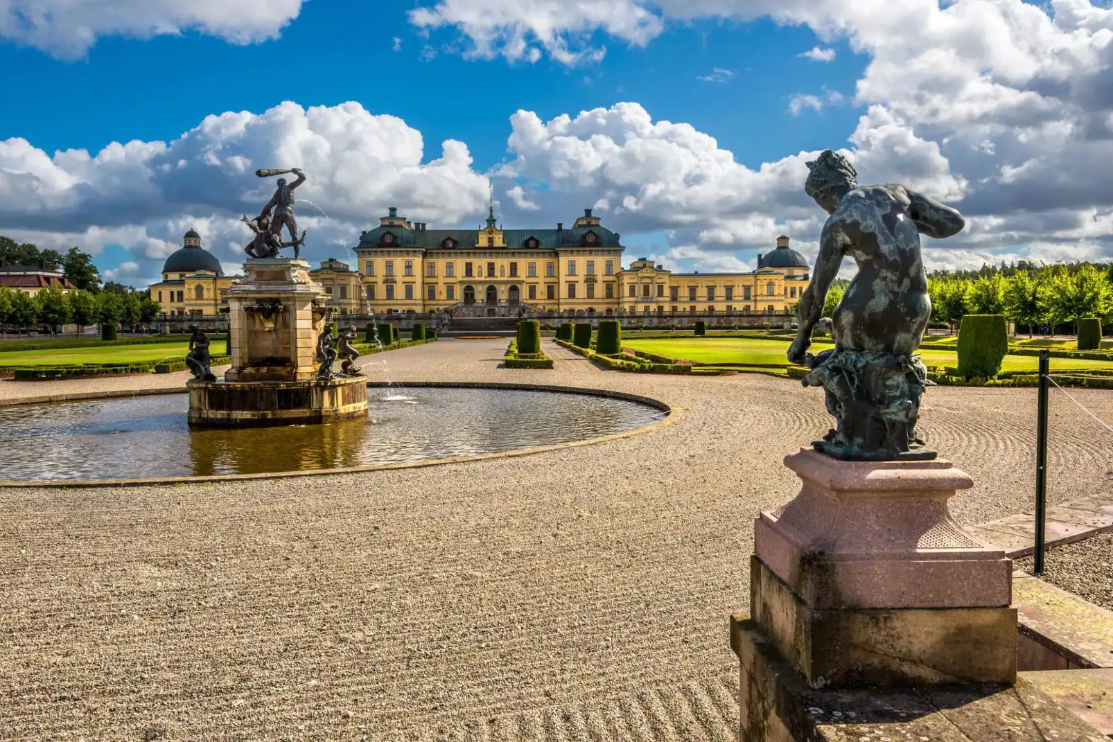 Drottningholm Palace in Sweden, with a central fountain, statues, and formal gardens in front