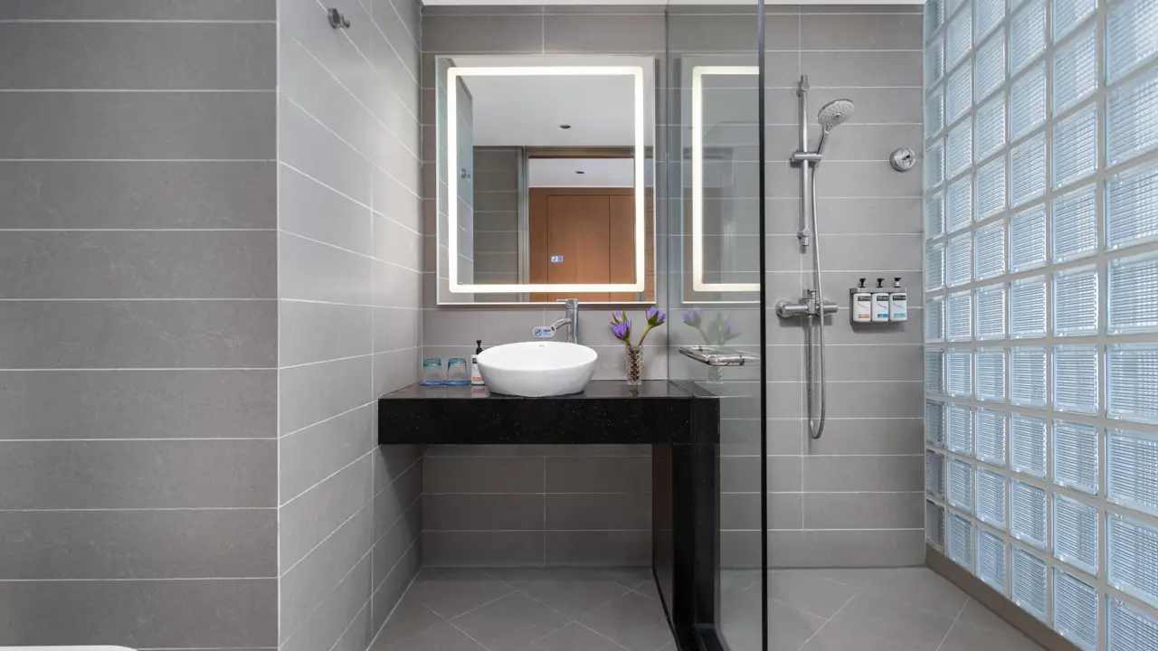 A stylish bathroom at the Holiday Inn Express Chengdu Gulou, designed with grey tiles, a glass-enclosed shower, a backlit mirror, and modern fittings for a clean, sophisticated look