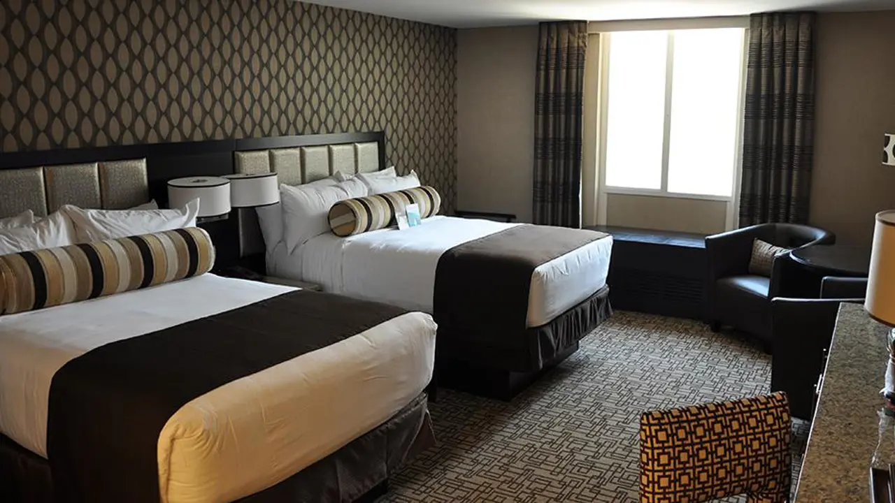 Comfortable twin double room at the Golden Nugget Hotel, Las Vegas, featuring two double beds with white linens, dark brown décor and patterned wallpaper