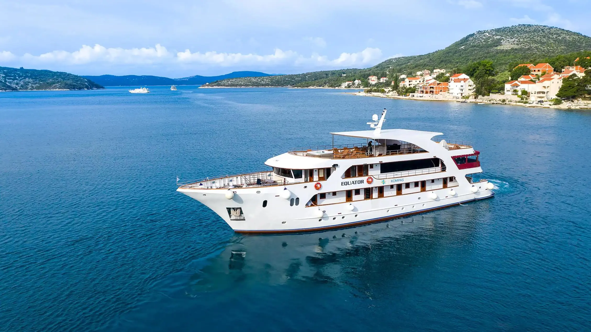 MS Equator cruise ship sailing on the calm blue sea off the coast of Croatia, with rocky shores and green hills in the background