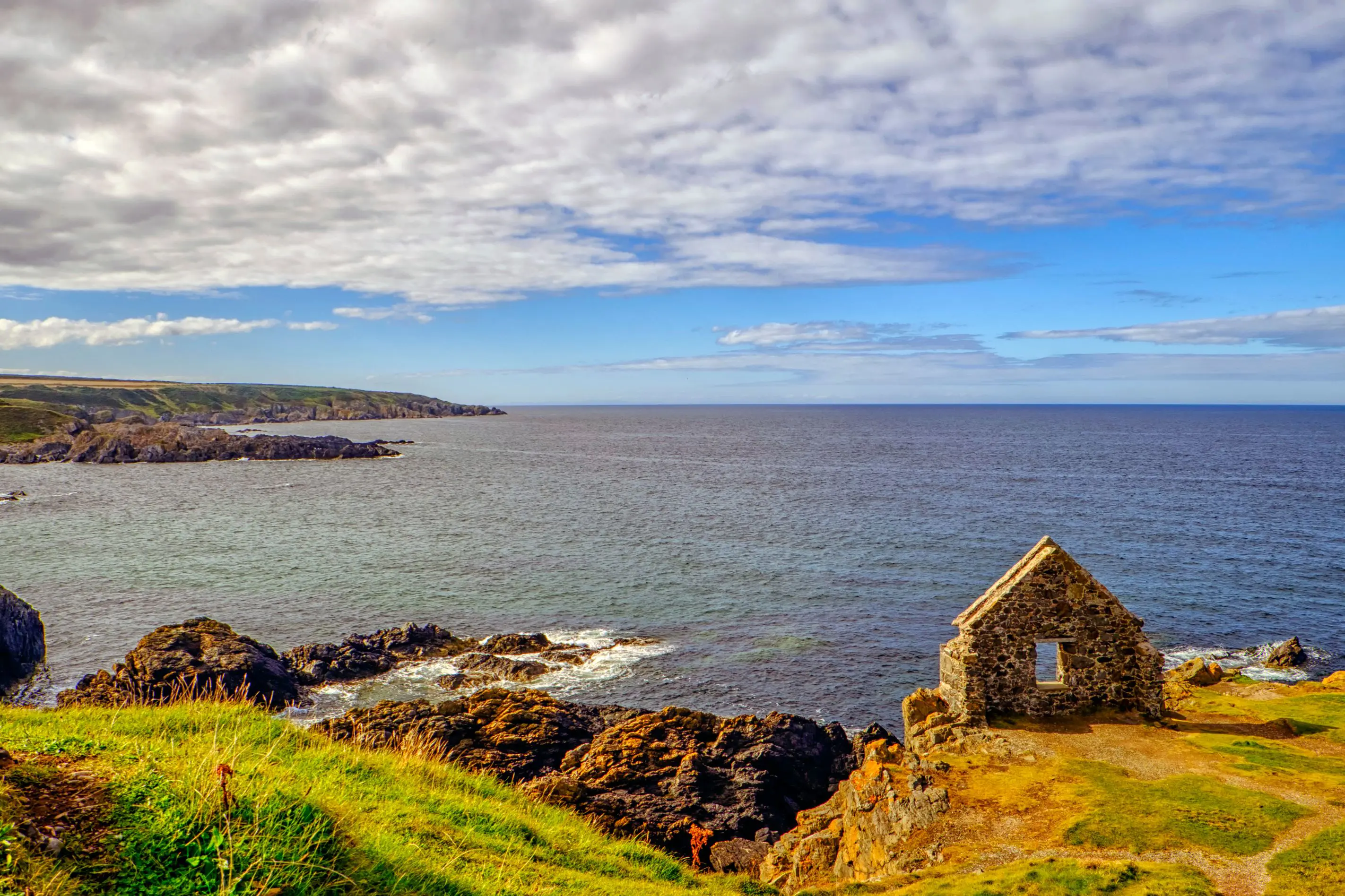 View of Moray Firth inlet, with grass and ruins of a building in the forefront