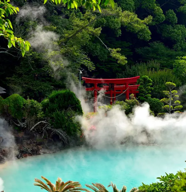 A steaming turquoise hot spring surrounded by lush greenery and a red torii gate in Beppu, Japan