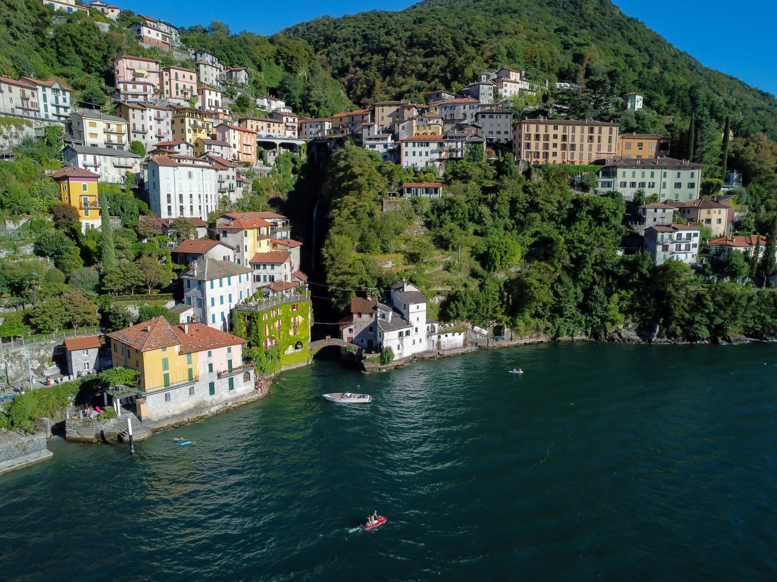 View of Nesso's waterfront, showing buildings up the mountain and boats on the water
