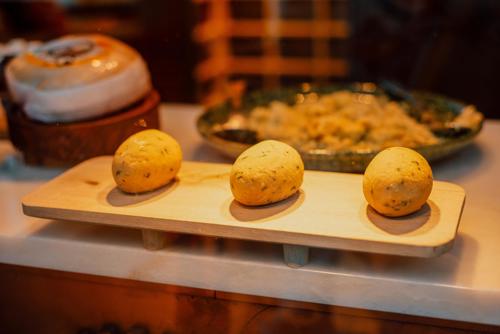 Three Pastéis de Bacalhau or Portuguese salt cod fritters placed on a wooden board in a restaurant display