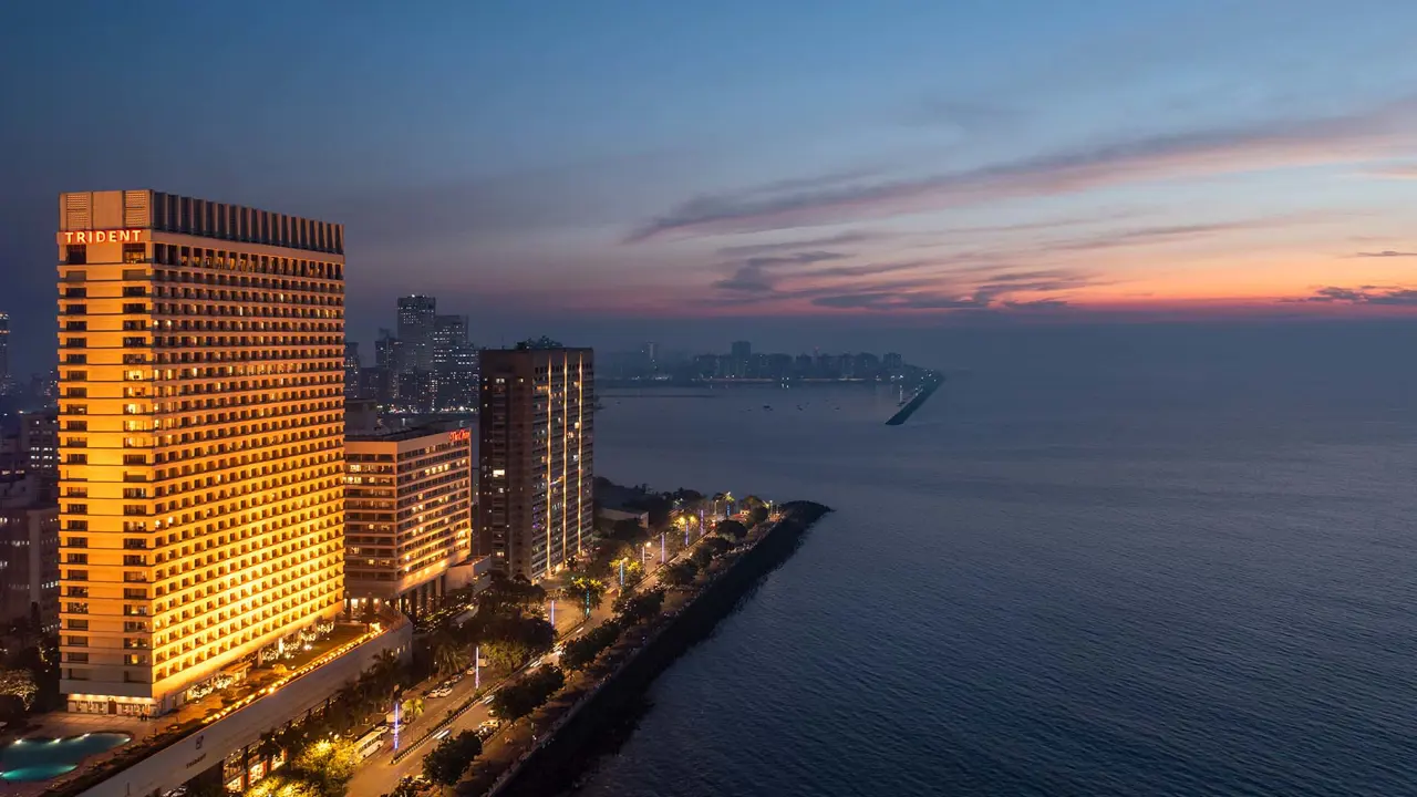 The Trident Nariman Point in Mumbai at night, a high-rise hotel tower glowing with exterior lights against the night sky