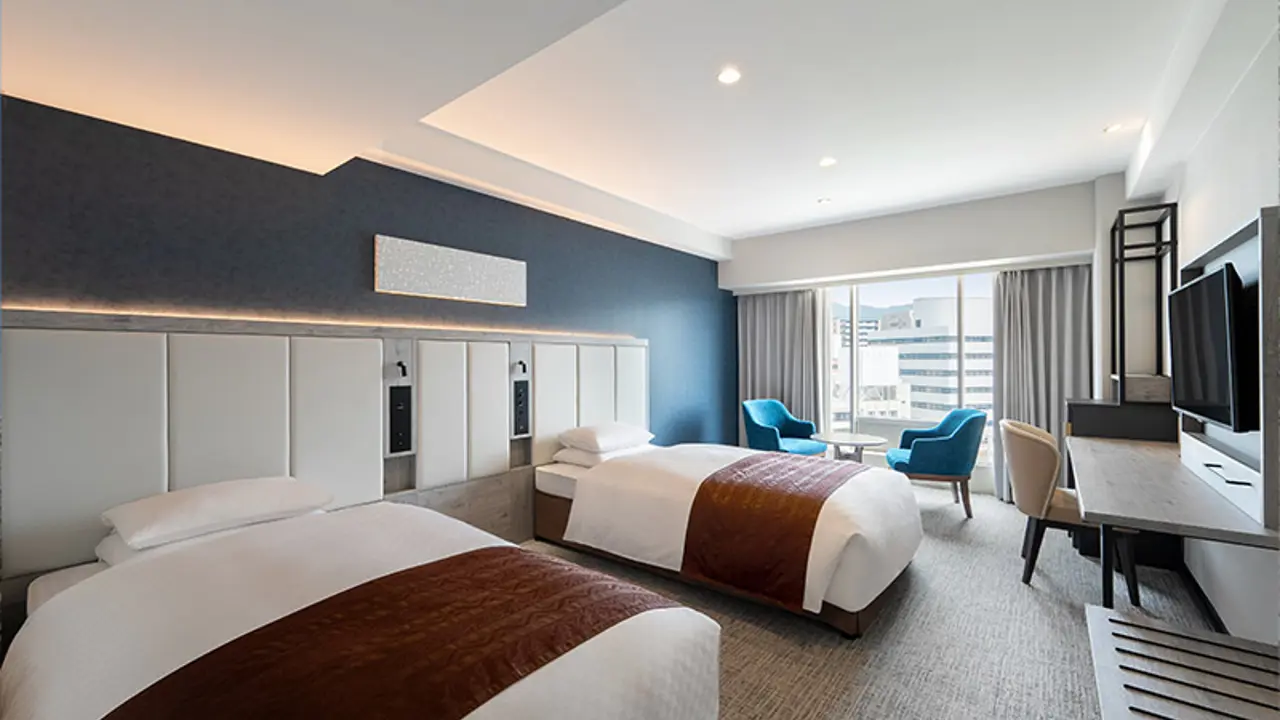 Contemporary twin room at Hotel New Nagasaki with two single beds, a dark accent wall, and city view through large windows