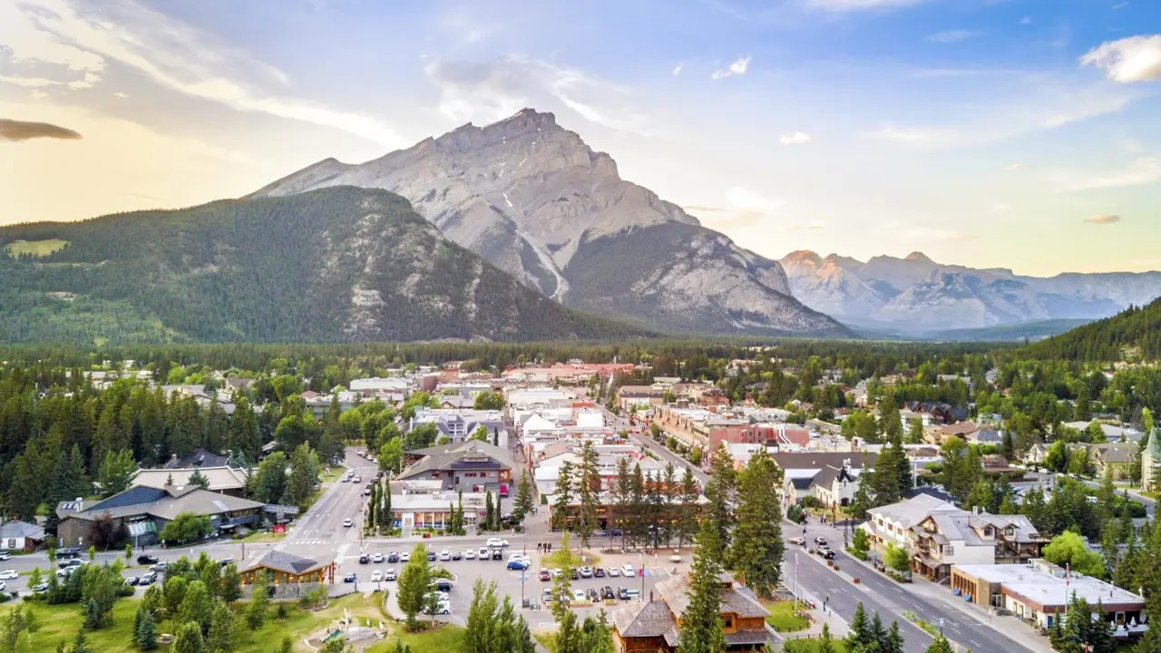 A stunning cityscape of Banff on a bright, clear day, surrounded by the towering peaks of the Canadian Rocky Mountains in Alberta