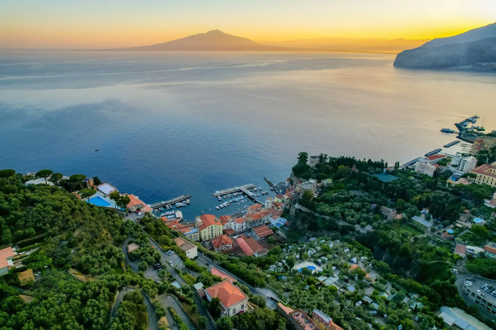 An aerial view of Sorrento on the Amalfi Coast, Italy at sunrise with Naples and Mount Vesuvius in the background
