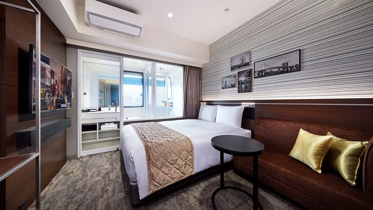 Double bedroom with an en-suite bathroom, decorated in warm brown and gold tones, featuring a large bed, elegant furnishings, and soft ambient lighting