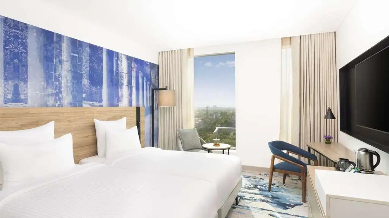A bright twin guest room at Novotel New Delhi City Centre with two beds and a city view