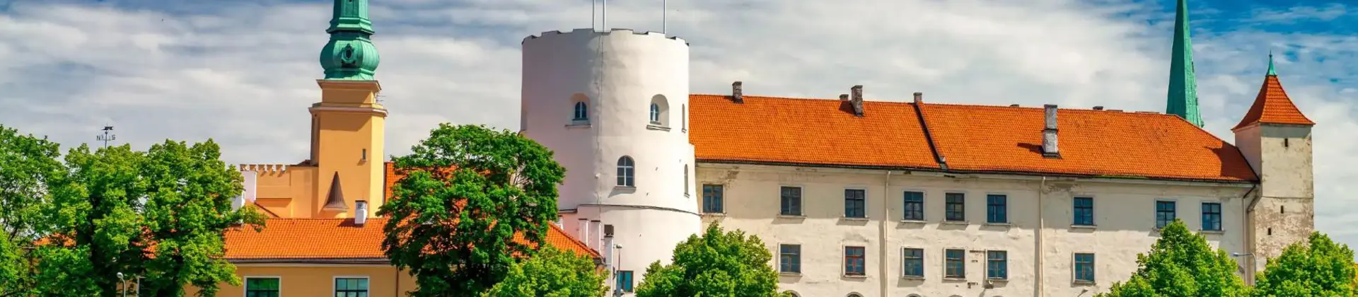 Historic Riga Castle with red rooftops and spires along the Daugava River