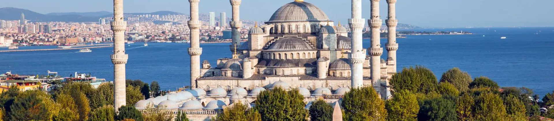 Exterior view of the Blue Mosque in Istanbul, Turkey, showing its domes and six minarets against a clear sky