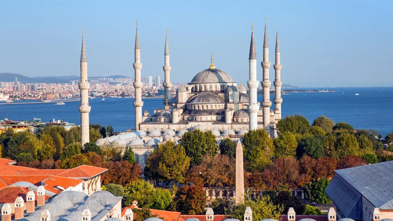 Exterior view of the Blue Mosque in Istanbul, Turkey, showing its domes and six minarets against a clear sky