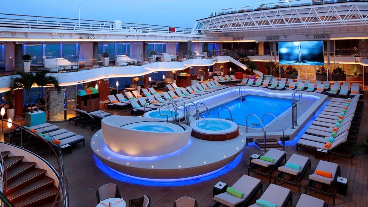 The deck area on board MS Koningsdam, featuring a rectangle swimming pool, sunbeds and three jacuzzis