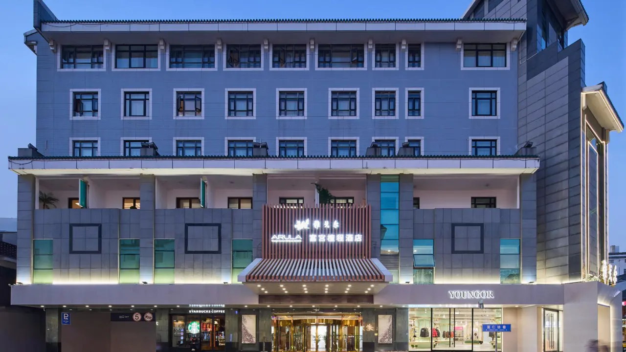 Exterior view of the modern, multi-story Youngor Central Hotel in China at dusk, featuring illuminated signage and a Starbucks on the ground floor